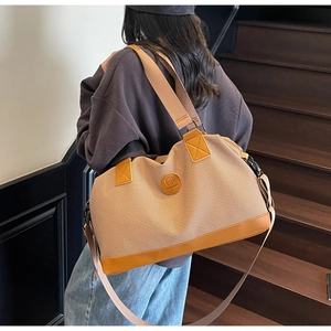 Detail of woven travel tote featuring leather trim and a branded logo patch on stairs