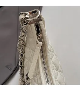 Detail of silver smooth zipper and quilted leather texture on white shoulder bag