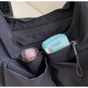 Detail view of large black nylon tote bag featuring multiple pockets and zipper closure