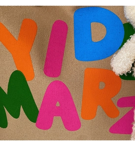Detailed macro view of khaki canvas texture with vibrant colorful letter prints and plush trim
