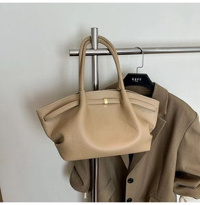 Detail of khaki pebbled leather tote bag with gold hardware on a minimalist hanger