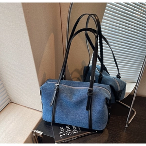 Dettaglio borsa tote in denim blu con manici in pelle nera e fibbie in argento lucido