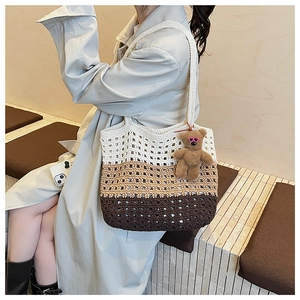 Close-up of a three-tone woven tote bag with a bear charm on a female model