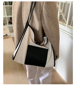 Detail of the high-capacity canvas tote bag featuring black leather front pocket and straps