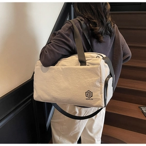 Detail of minimalist cream canvas travel bag with durable black straps and brand logo