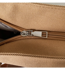 Detail of silver metal zipper and branded interior lining on canvas tote bag