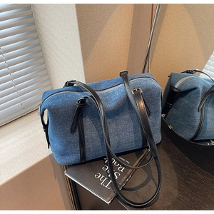 Dettaglio della borsa Boston in denim con cinturini in pelle su un libro nero