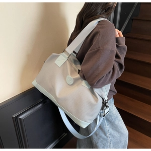 Detail of adjustable shoulder strap and fabric texture on grey travel bag