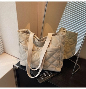 Detail of beige quilted tote bag with diamond pattern and brand label in a stylish setting