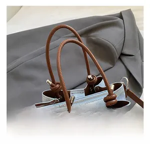 Detail view of the denim bucket bag with brown braided knot handle and silver hardware