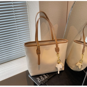 Detail of cream tote bag with brown leather trim and cute elephant charm pendant