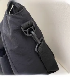 Close-up of durable black plastic hook and thick nylon shoulder strap on messenger bag