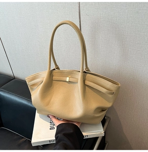Detail of beige litchi grain leather tote with pleated design and gold metal buckle