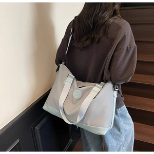 Detailed view of grey and mint travel bag showing adjustable shoulder strap and leather logo
