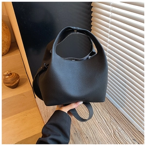 Close-up of black lychee grain leather bucket bag with seamless handle and modern minimalist style