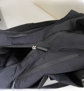 Detail view of smooth black zippers and durable nylon fabric on the large shoulder bag
