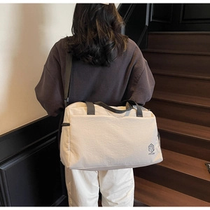 Detailed back view of a large cream canvas travel bag with black straps and logo