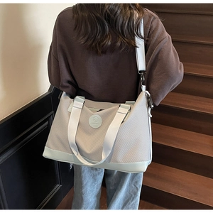 Detail of grey waffle weave travel tote with adjustable strap on wooden stairs