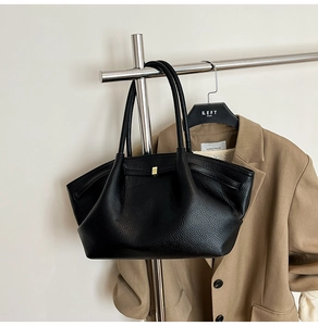 Detail of black pebbled leather tote bag with elegant gold buckle on a stylish hanger