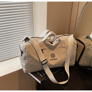 Light grey waterproof travel bag with double handles and adjustable shoulder strap detail