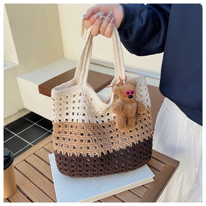Macro view of a tricolor crochet beach tote with mesh hollow design and a cute bear charm