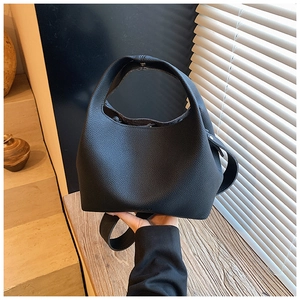 Detail of black lychee grain leather bucket bag with top handle and wood decor