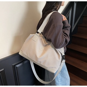 Detailed back view of a large cream travel tote bag worn by a model on stairs