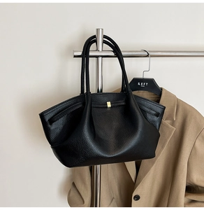 Detail of black lychee grain leather tote bag with pleated design and gold buckle
