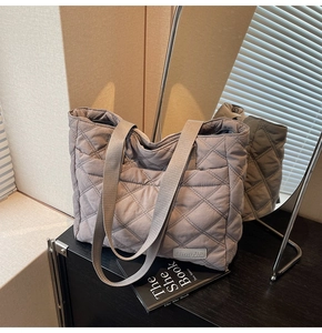 Close-up of diamond quilted tote bag with NingJia label on soft dark grey fabric