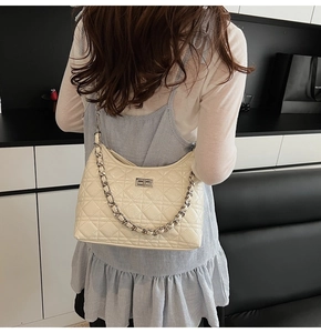 Detail view of quilted cream leather shoulder bag with silver chain and turn-lock closure