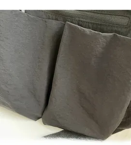 Close-up of black nylon crossbody bag featuring dual front pockets and soft wrinkled texture