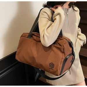 Detail of dark brown travel bag with durable texture, sturdy handles and zip pocket