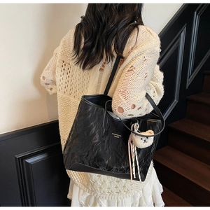 Detailed view of black textured tote bag with cute bear charm and fashion branding