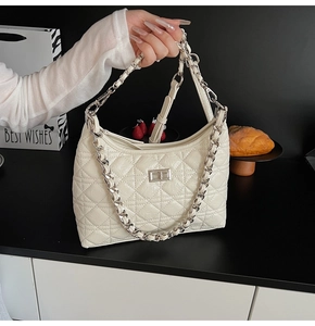 Close-up of cream quilted leather bag with silver chain strap and metal turn-lock closure