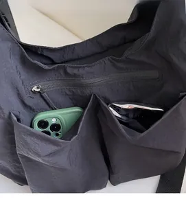 Detail of black nylon tote bag showing dual front pockets with metal zippers and phone storage