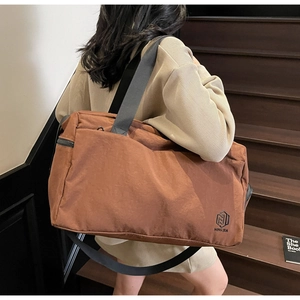 Detailed view of an orange-brown travel bag with shoulder strap on wooden stairs