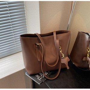 Detail of dark brown leather tote bag with elephant charm and brand embossing