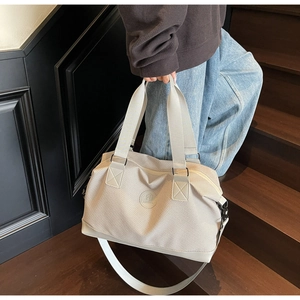 Detail of waffle-textured beige travel bag with reinforced handles and removable shoulder strap