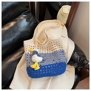 Macro shot of tricolor woven tote bag with a cute plush seagull charm on a chair