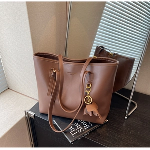Detail of dark brown leather tote bag with elephant charm and adjustable shoulder strap