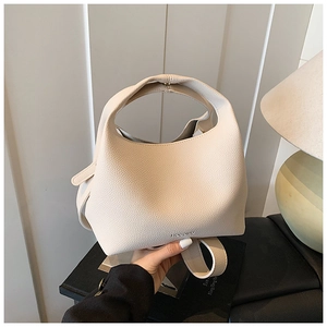 Detailed close-up of beige lychee grain bucket bag with wide integrated handle and branding