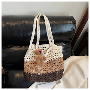 Close-up of three-tone gradient woven tote bag with a cute teddy bear charm on leather sofa