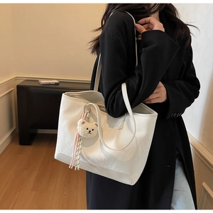 Detail of off-white tote bag featuring delicate leather texture and cute bear pendant