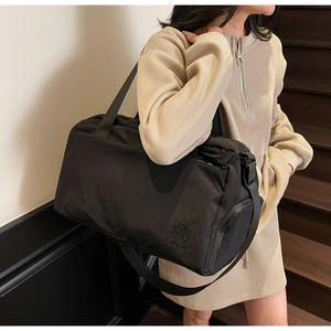 Black multi-functional travel bag with adjustable strap shown in a minimalist interior