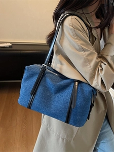 Borsa tote in denim blu con manici neri mostrata in un ambiente interno minimalista