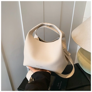 Close-up of beige lychee grain leather bucket bag with hollow handle and ROCOMU branding
