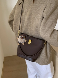 Borsa a secchiello in pelle marrone con fibbia dorata e ciondolo a agnello indossata