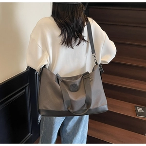 Close-up of a large grey travel tote bag with reinforced handles on a wooden staircase