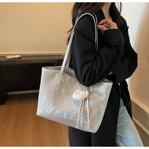Detail of light gray glossy tote bag with crinkle texture and plush bear charm