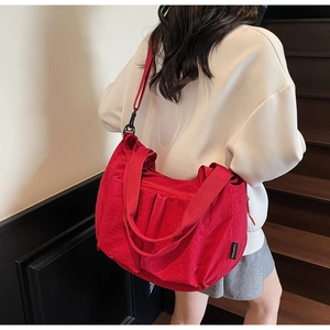 Detail showing red large-capacity tote bag with pleated design and black brand label